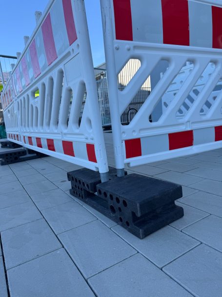 Bausperre mit roten und weißen Markierungen auf einem Gehweg.