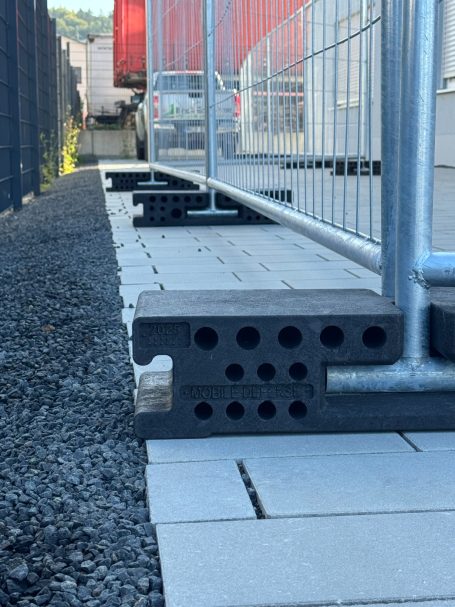 Blick auf eine Baustelle mit Pflastersteinen und einem Zaun aus Metall.